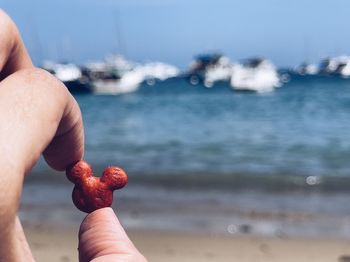 Midsection of person holding ice cream on beach