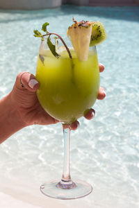 Hand holding drink by the pool