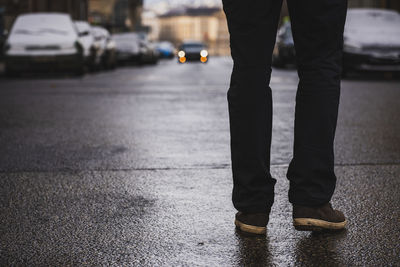 Low section of man standing on road