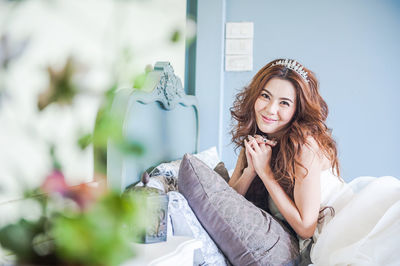 Portrait of smiling young woman on bed at home