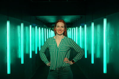 Portrait of smiling young woman standing against wall