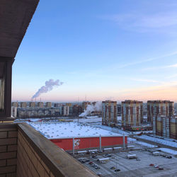 Snow covered buildings in city against sky during sunset