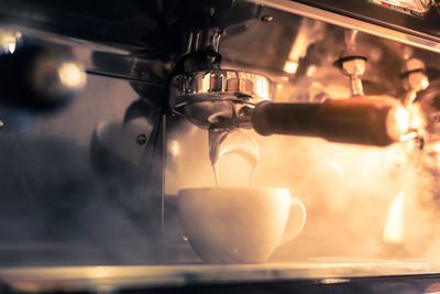 Close-up of machinery pouring coffee in cup at cafe