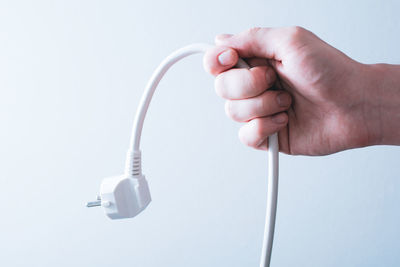 Close-up of hand holding smart phone over white background