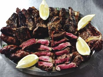 Close-up of cooked meat with lemon slices in plate on table