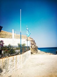 View of flag on beach against clear blue sky