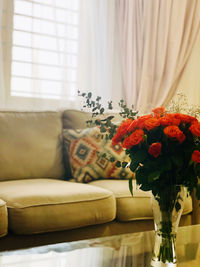 Midsection of woman with flowers on sofa at home
