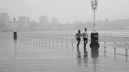 People walking on sidewalk by sea