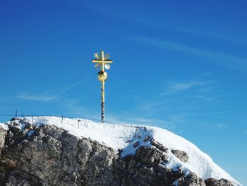 Low angle view of cross on rock against sky