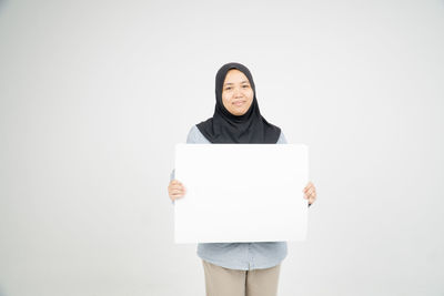 Portrait of smiling young woman standing against white background