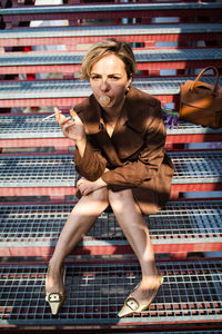 Portrait of young woman sitting on stairs and smoking