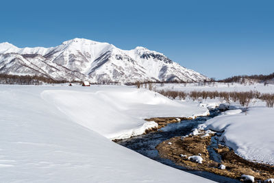 Scenic view of frozen lake against clear blue sky