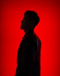 Side view of silhouette man against red background