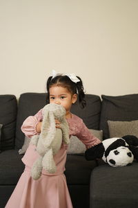 Cute baby girl sitting on sofa at home