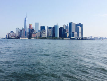 Sea by modern buildings in city against sky