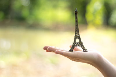 Cropped hand holding replica eiffel tower