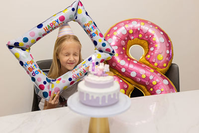 Cheerful girl sitting by balloon during birthday