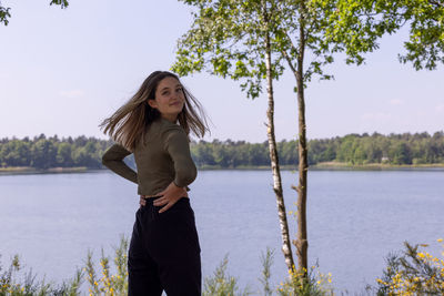 Young woman standing against lake