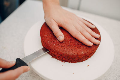 Woman cutting red velvet cake on table