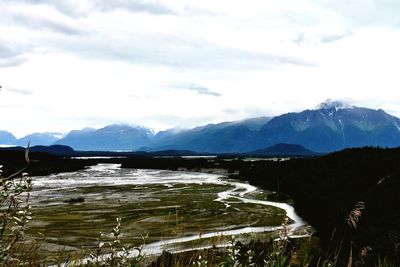 Scenic view of river by mountains against sky