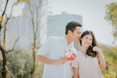 Smiling boyfriend whispering in girlfriend ear at park