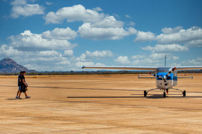 Man and woman at airport runway against sky