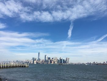 City at waterfront against cloudy sky