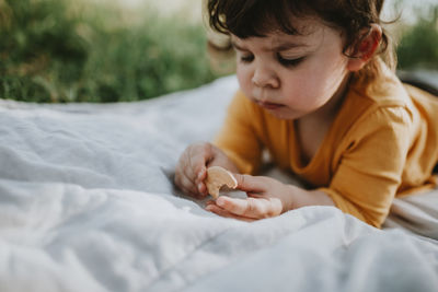 Boy looking away while lying on bed