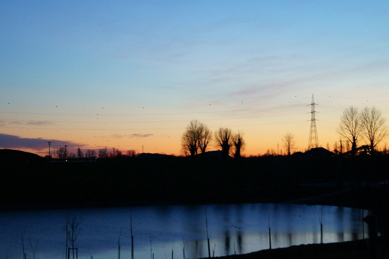 SILHOUETTE BARE TREES BY LAKE AGAINST SKY