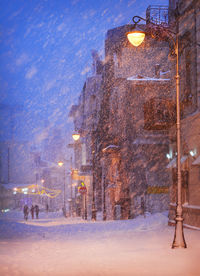 Illuminated street light on snow against sky at night