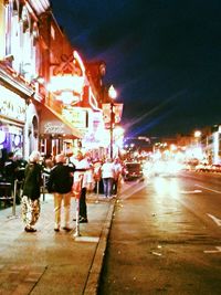 People standing on illuminated city street at night
