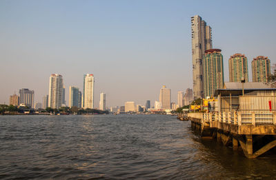 River by buildings against clear sky in city