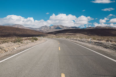 Empty road by mountains against sky