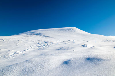 Scenic view of snowcapped mountains against clear blue sky