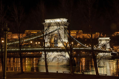 Illuminated bridge over river at night