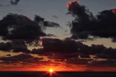 Scenic view of sea against dramatic sky during sunset