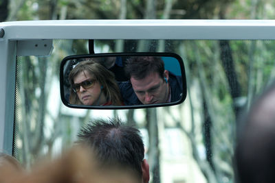 Portrait of man photographing woman in car