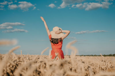 Rear view of woman standing on field against sky