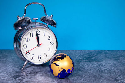 Close-up of clock on table against blue background