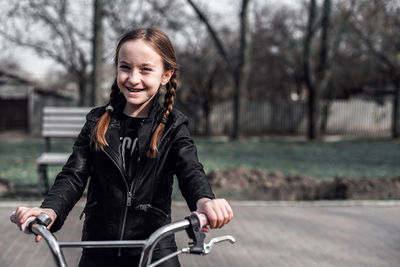 Smiling girl with bicycle at park