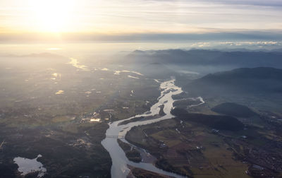 Aerial view of land and sea against sky during sunset