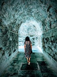 Rear view of woman walking in tunnel