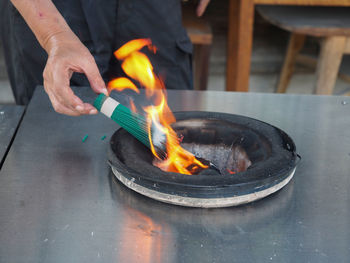 Midsection of man preparing burning fire