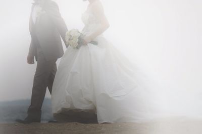 Side view of newly wed couple walking on landscape