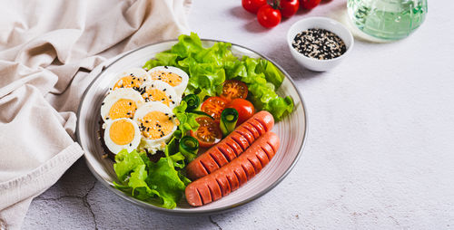 Fried sausages, tomatoes, lettuce and a sandwich with a boiled egg on a plate web banner