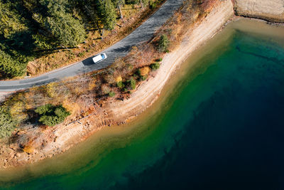 Aerial view of car on road by lake and forest in autumn