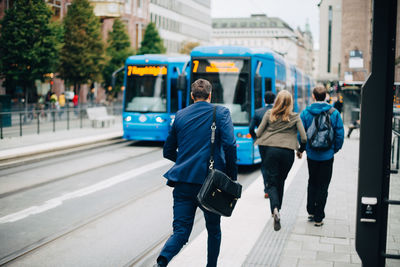 Rear view of businessman running towards cable car on street in city