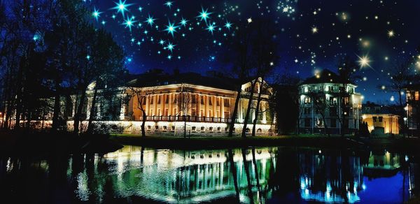 Illuminated building by river at night