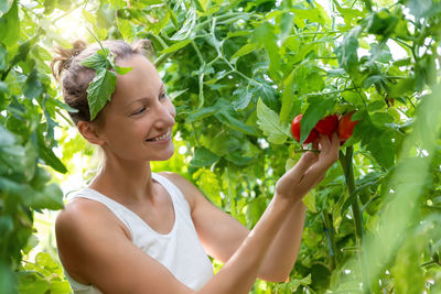 Side view of young woman looking away against plants