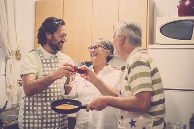 Happy family toasting red wine in kitchen at home